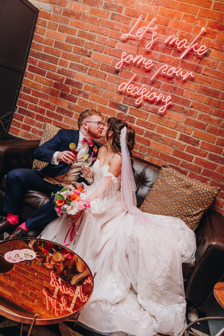 Emma and Jake kissing under a neon sign which reads Let's Make Some Pour Decisions at new craven hall leeds